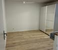 Empty room with wooden flooring, white walls, and a built-in wardrobe with mirrored doors. A round ceiling light fixture is visible.
