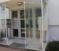 Entrance area of a building with glass doors, mailboxes, and a small covered porch.