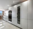 Modern kitchen with white cabinets, stainless steel appliances, a wine cooler, and a large window offering a city view.