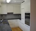 Modern kitchen with white cabinets, granite countertops, stainless steel sink and faucet, and built-in oven.