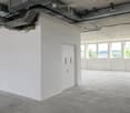 Empty room with white walls, concrete floor, large windows, and a white door.