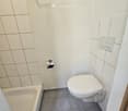 Modern bathroom with a toilet, bathtub, towel, toilet paper holder, and a handrail on the wall.