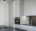Modern kitchen with sleek grey cabinets, stainless steel appliances, and a black countertop.