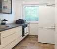 Modern kitchen with white cabinets, stainless steel sink, refrigerator, oven, and various kitchen utensils.