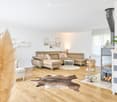 Modern living room with light-colored leather sofa, ottoman, coffee table, fireplace, and decorative elements.
