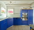 Modern kitchen with blue cabinets, granite countertops, stainless steel sink and faucet, built-in oven, and decorative jars on the counter.