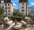 Balcony with two wicker sofas, a round coffee table, potted plants, and lanterns.
