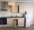 Modern kitchen with white cabinets, stainless steel appliances, and a black countertop.