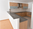 Modern kitchen with light wooden cabinets, granite countertop, and built-in appliances including a stove and range hood.