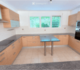 Modern kitchen with light wood cabinets, granite countertops, built-in oven and microwave, and a central island table.