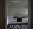 Modern kitchen with white cabinets, black countertop, built-in oven, and a decorative black and white tile floor.