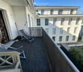 Balcony with dark tiled floor, metal railing, and two lounge chairs.