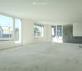 Empty room with concrete floor, white walls, large windows, and a sliding glass door leading to a balcony.