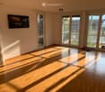 Empty room with wooden flooring, large windows, and a balcony door leading to a small outdoor area.