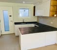 Modern kitchen with white cabinets, black countertops, and a sink. Features a window and a door leading outside.