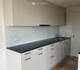 Modern kitchen with white cabinets, black countertop, and a sink with a faucet.