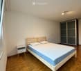 Minimalist bedroom with a wooden bed, blue mattress, white pillows, a small nightstand, and a modern wardrobe with mirrored doors.