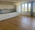 Modern kitchen with white cabinets, wooden flooring, and large windows offering a scenic view.