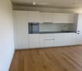 Modern kitchen with white cabinets, wooden flooring, and stainless steel appliances including an oven and a sink with a faucet.
