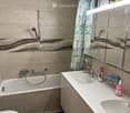 Modern bathroom with a bathtub, double sink, large mirror, and a shower area with a curtain.