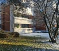 Modern two-story building with white and red brick facade, large windows, and snow-covered ground.
