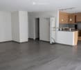 empty room, white walls, gray tiles, kitchen island, cabinets, refrigerator, microwave, countertop