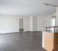 empty room, white walls, gray floor, kitchen area with granite countertop, cabinets, windows with blinds