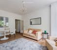 Living room with light-colored sofa, coffee table, dining table, chairs, and a large mirror on the wall.