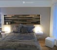 Modern bedroom with a large bed, wooden headboard, nightstands, and a fur throw on the bed.