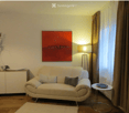 Modern living room with a cream-colored sofa, side table, floor lamp, and decorative items on a sideboard.