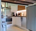 Modern kitchen with white cabinets, stainless steel appliances, and exposed wooden beams on the ceiling. Features include a refrigerator, oven, dishwasher, and a range hood.