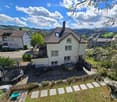 A peaceful garden and outdoor area with a trampoline, patio furniture, and a scenic mountain view in the background.
