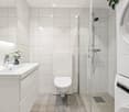 Modern bathroom with white tiles, a sink with a chrome faucet, a toilet, a glass-enclosed shower, and a stacked washer and dryer unit.