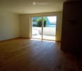 Empty room with wooden flooring and large sliding glass doors leading to an outdoor area.