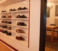 A well-organized shoe storage area with multiple shelves filled with various pairs of shoes, a small table, and a chair in the background.