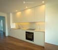 Modern kitchen with white cabinets, marble backsplash, wooden flooring, and built-in appliances including a sink, faucet, and oven.