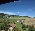 A scenic rural landscape with green fields, scattered houses, and a clear blue sky.