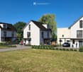 A modern residential complex with three contemporary houses, featuring clean lines, large windows, and well-maintained landscaping.