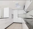 Modern kitchen with white cabinets, dark countertops, and stainless steel sink and faucet.
