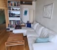 Modern living room with white sectional sofa, wooden coffee table, bookshelf, floor lamp, and decorative pillows.