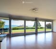 Bright, open-plan room with wooden flooring, large sliding glass doors leading to a patio, and a dining area with a table and chairs.