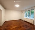 Empty room with wooden flooring, white walls, large windows, and built-in cabinets.