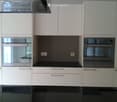 Modern kitchen with white cabinets, stainless steel oven, and black countertops.