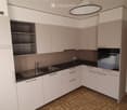 Modern kitchen with white cabinets, black countertop, stainless steel sink, and built-in oven.