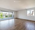 Empty room with wooden flooring, white walls, large sliding glass doors leading to a balcony, and windows with white frames.