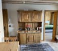 A rustic kitchen with wooden cabinets, a dining table, chairs, and a candle holder on the counter.
