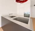 Modern kitchen with white cabinets, a stainless steel sink, a sleek induction cooktop, and a minimalist design.