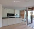 Modern kitchen with white cabinets, black countertop, and a sink with a faucet. Large glass sliding doors lead to a balcony area.