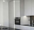 Modern kitchen with grey cabinets, stainless steel oven, sink with faucet, and a teapot on the counter.
