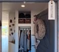 Cozy hallway with a built-in coat closet, decorative items, and a welcoming sign. Features a round ceiling light and a woven wreath on the door.